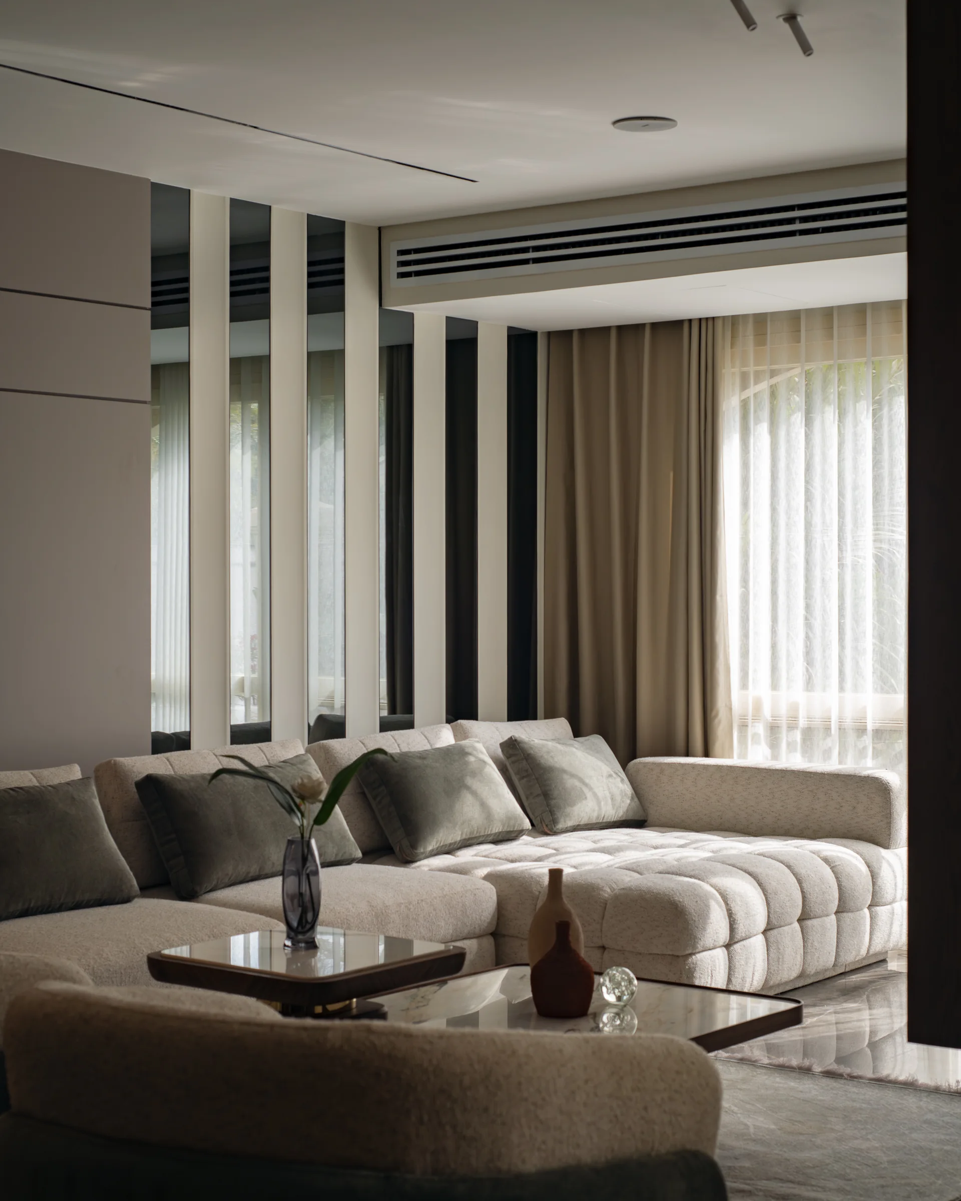 Seating group with a low stone table and pleated curtains.