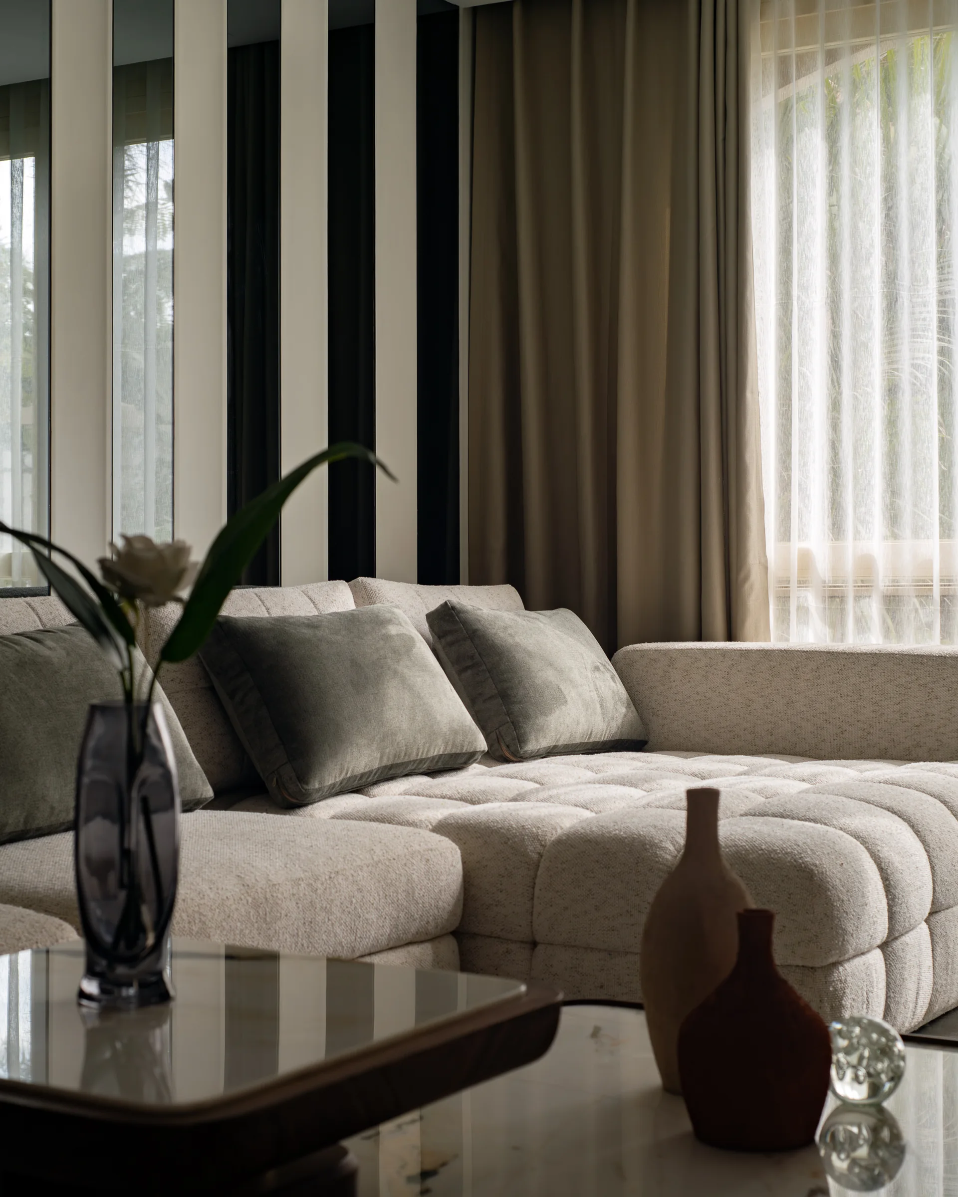Sofa corner with a glass vase and a stone bowl on the table.