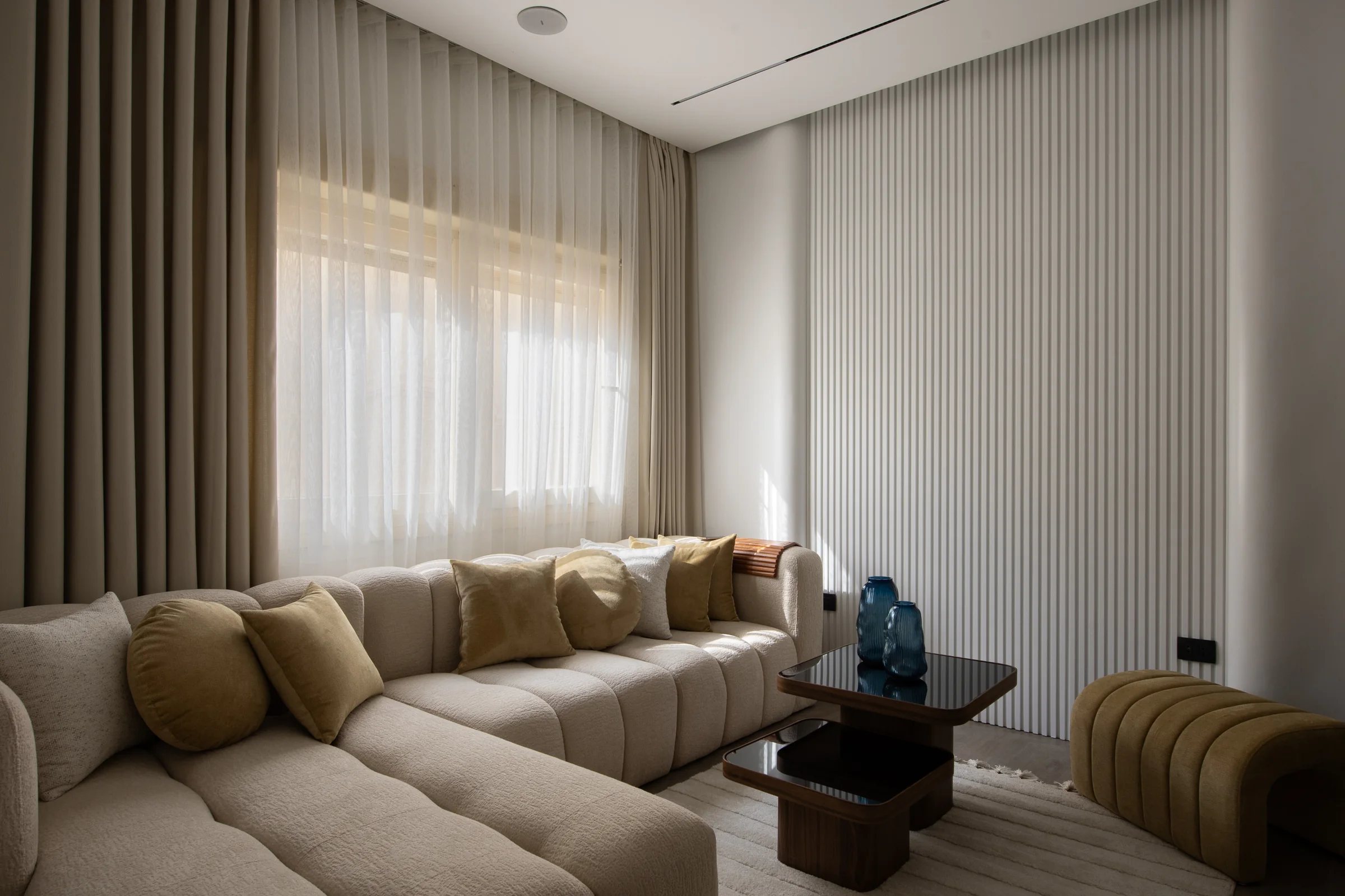 Long sofa in ivory bouclé with blue glass vessels on the table.