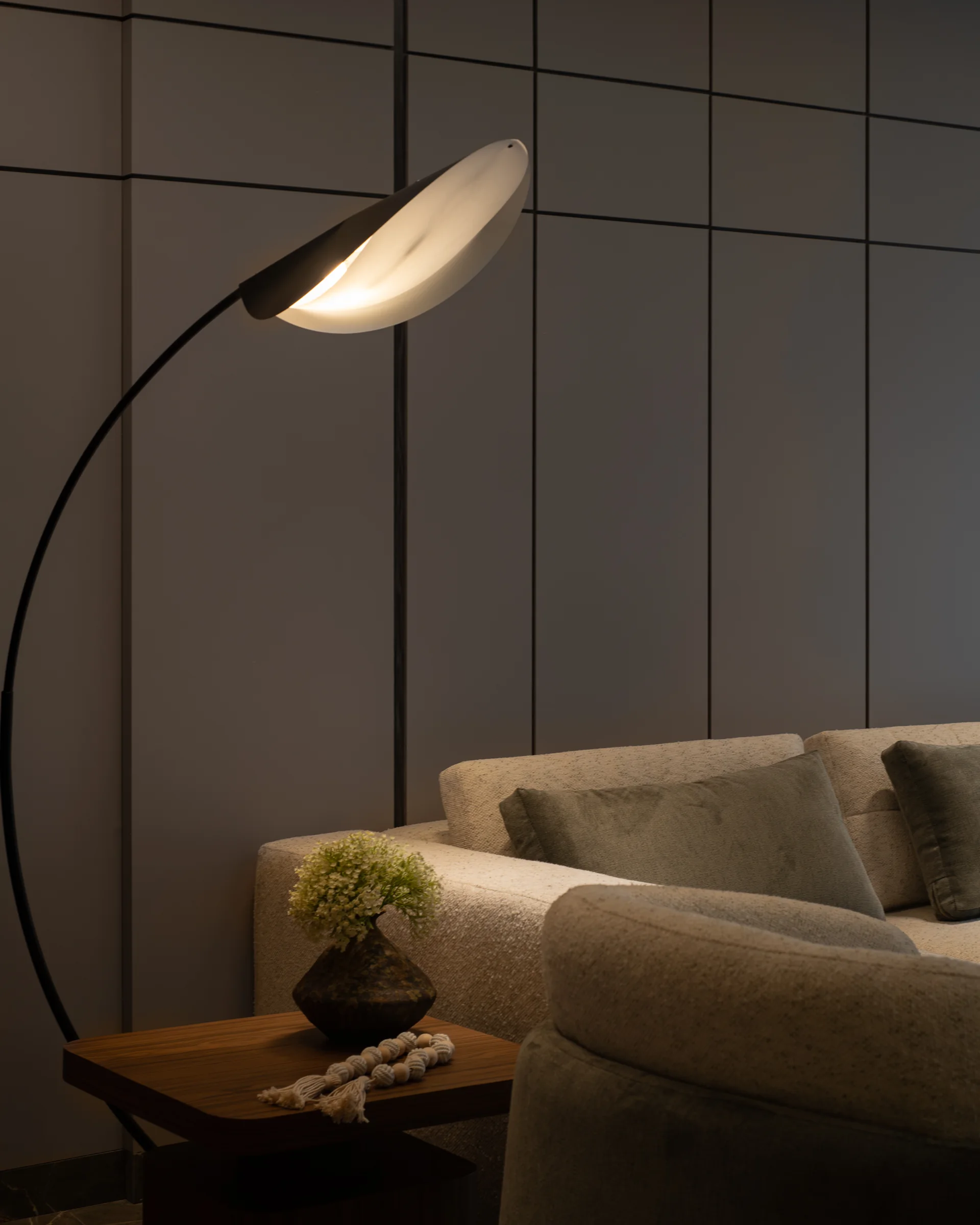 Arc lamp head over the sofa arm, shot close in low light.