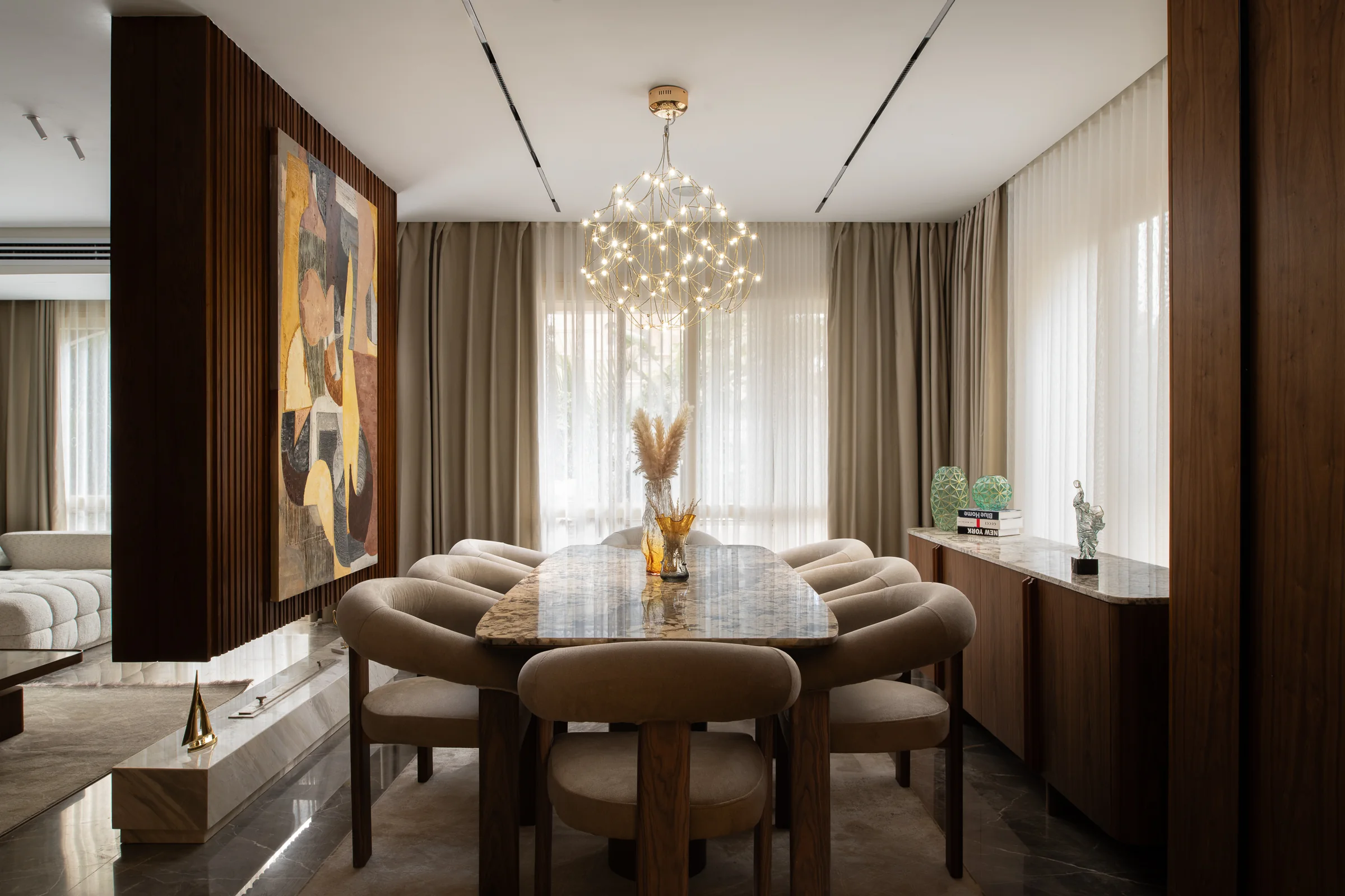 Dining room under a cluster pendant, artwork on the panelled wall.