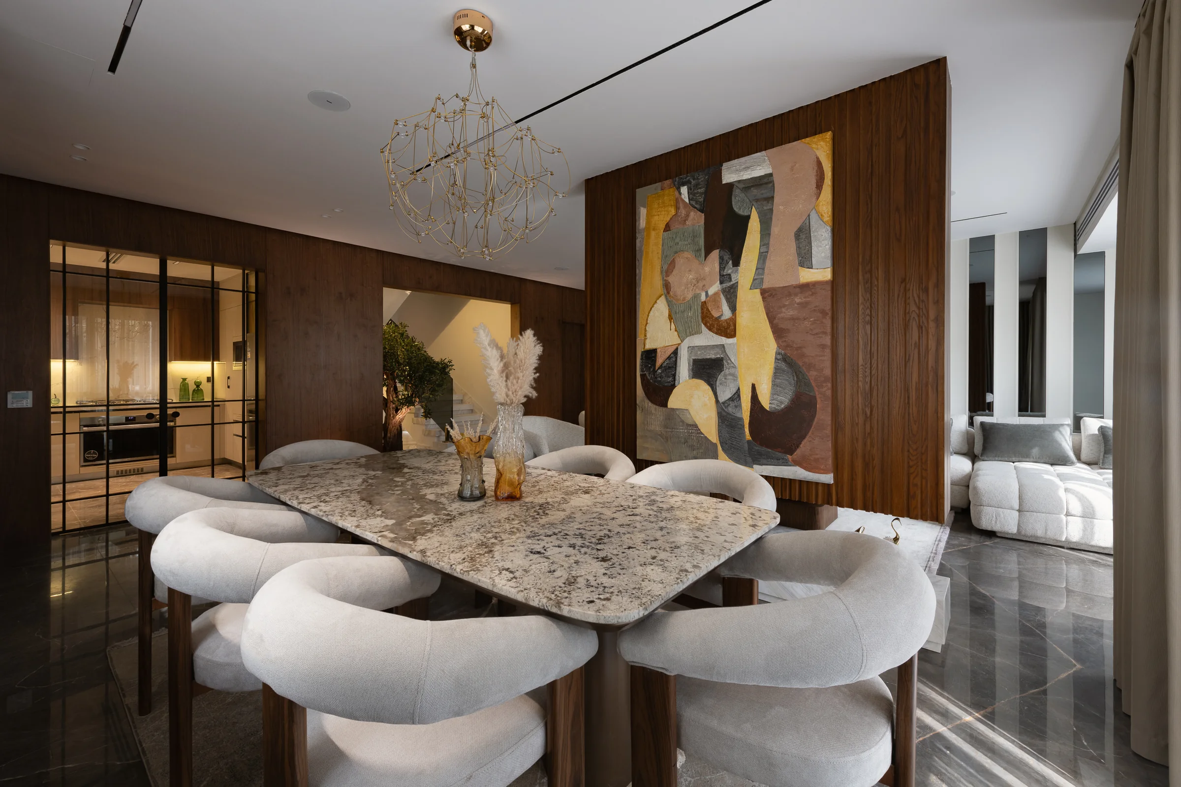Dining room wide, marble table and curved upholstered chairs.