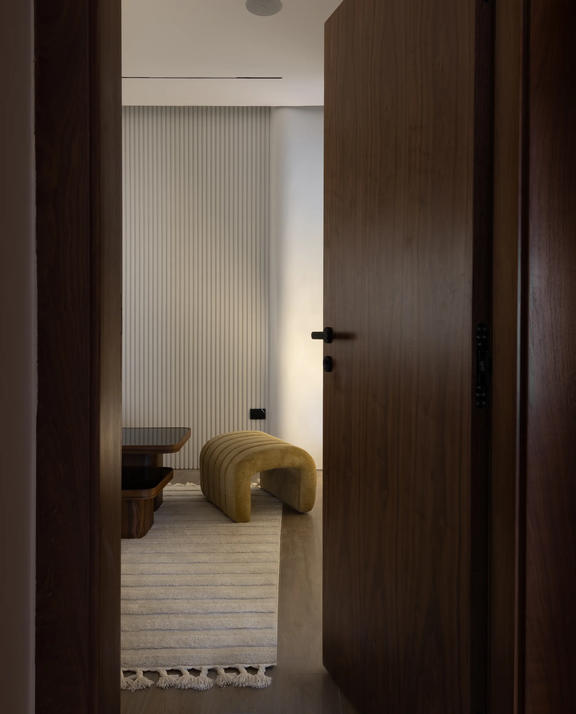 Bedroom glimpsed past a walnut door.
