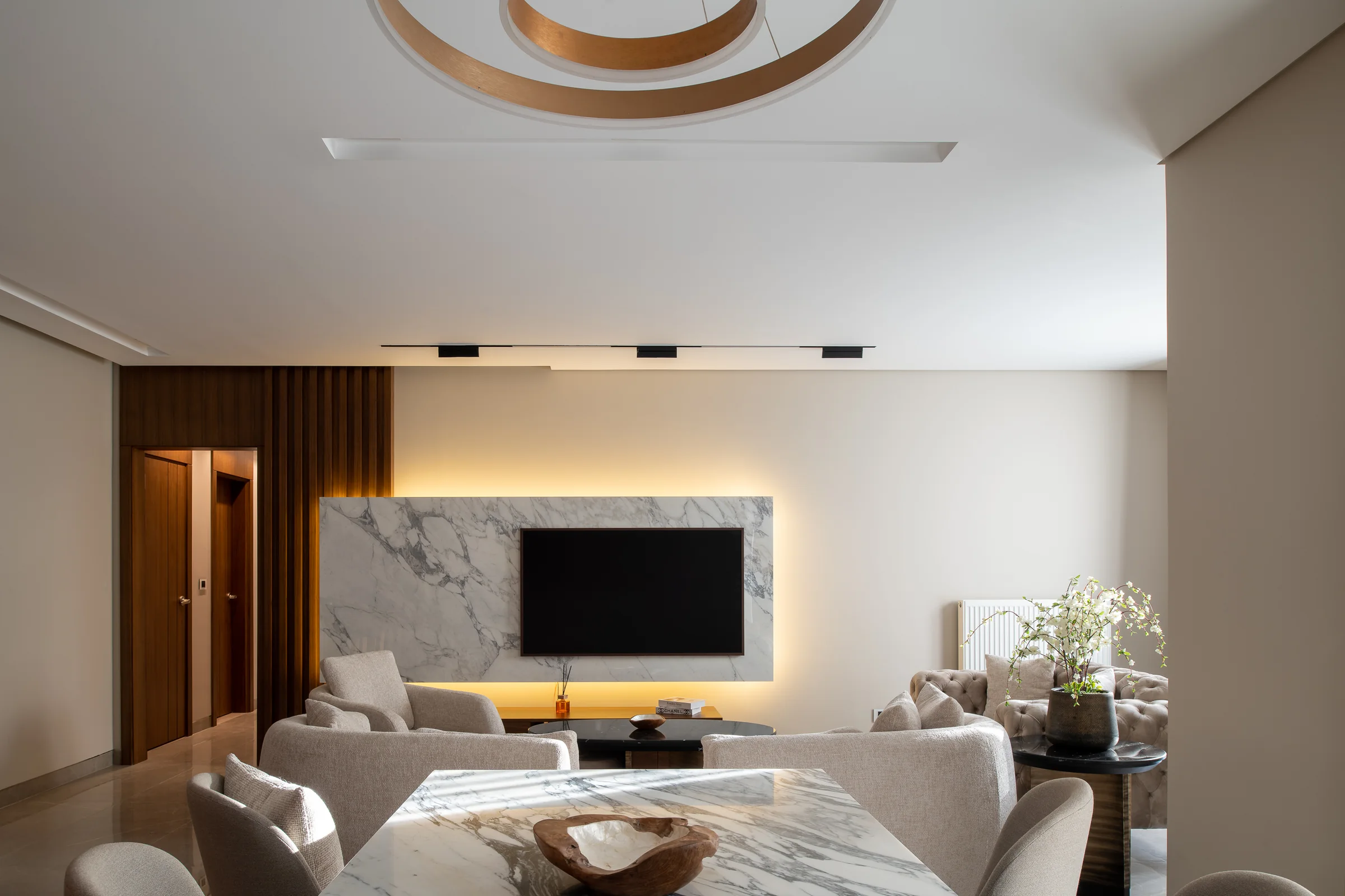 Living room wide: marble media wall, warm cove, curtains drawn back.