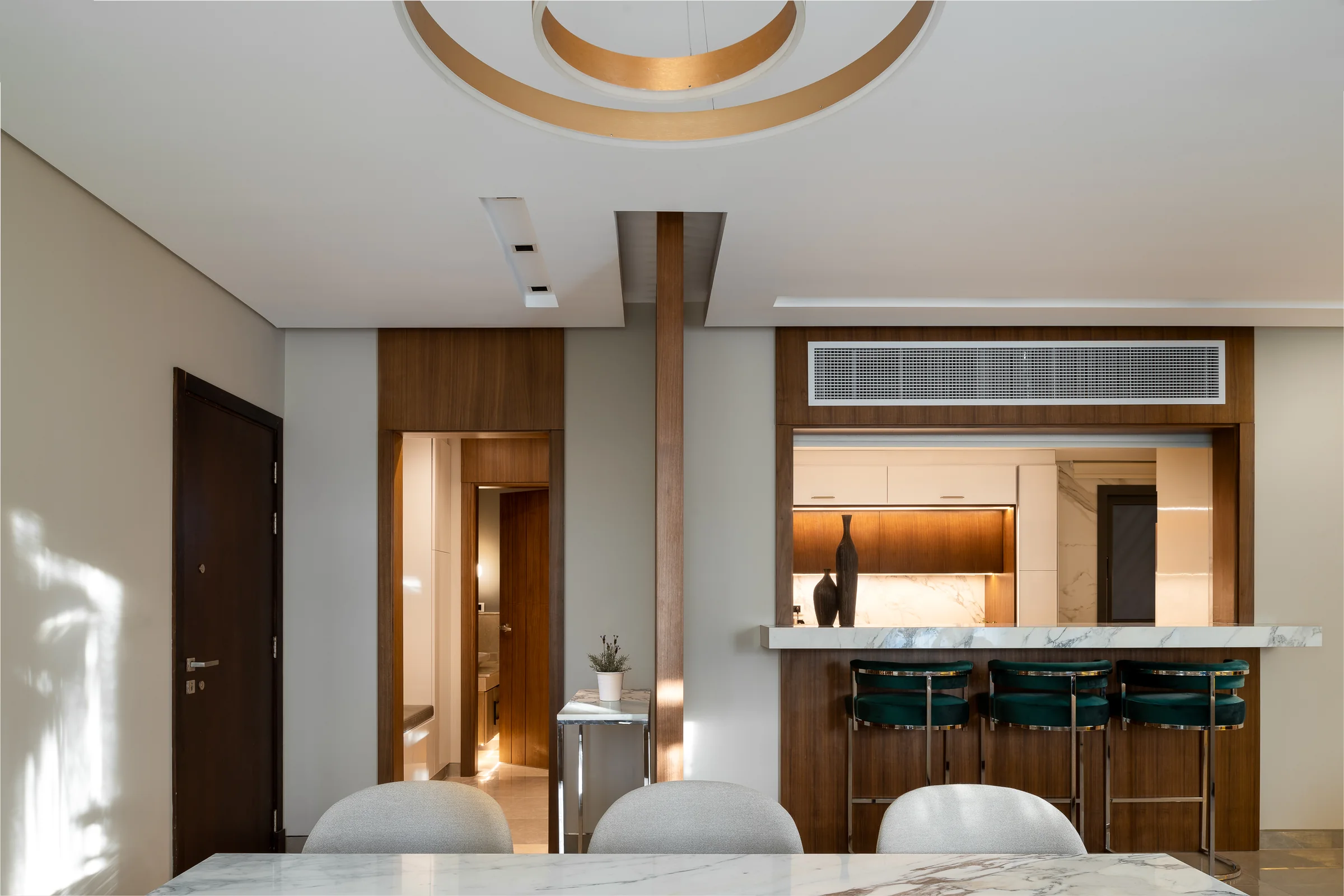 Dining and kitchen together, brass stools at the counter.