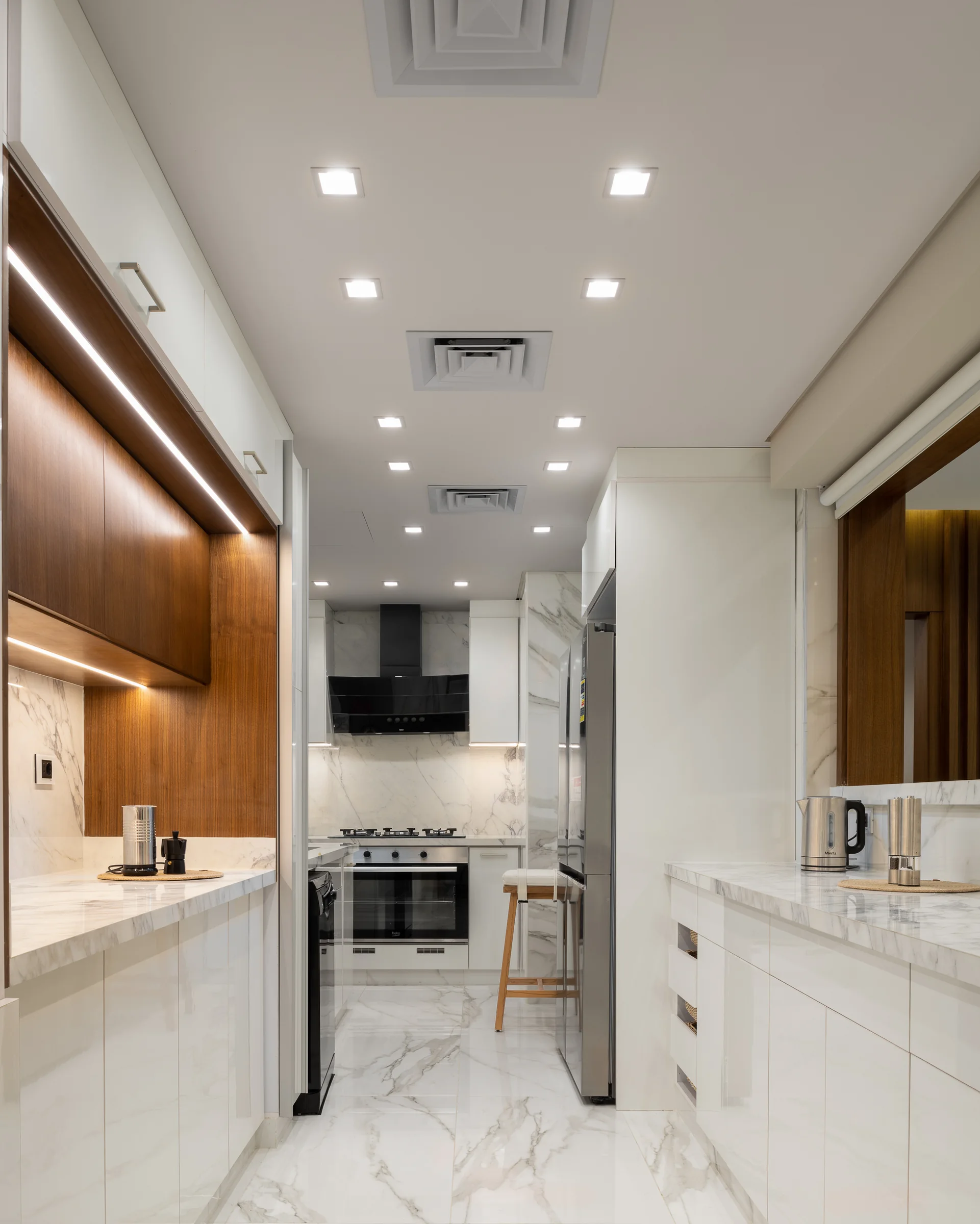 Kitchen along its length, marble and white joinery.