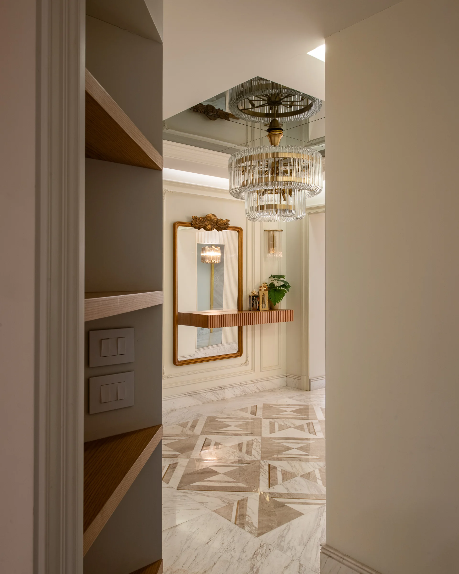 The entry corridor, gilt mirror and chandelier beyond.
