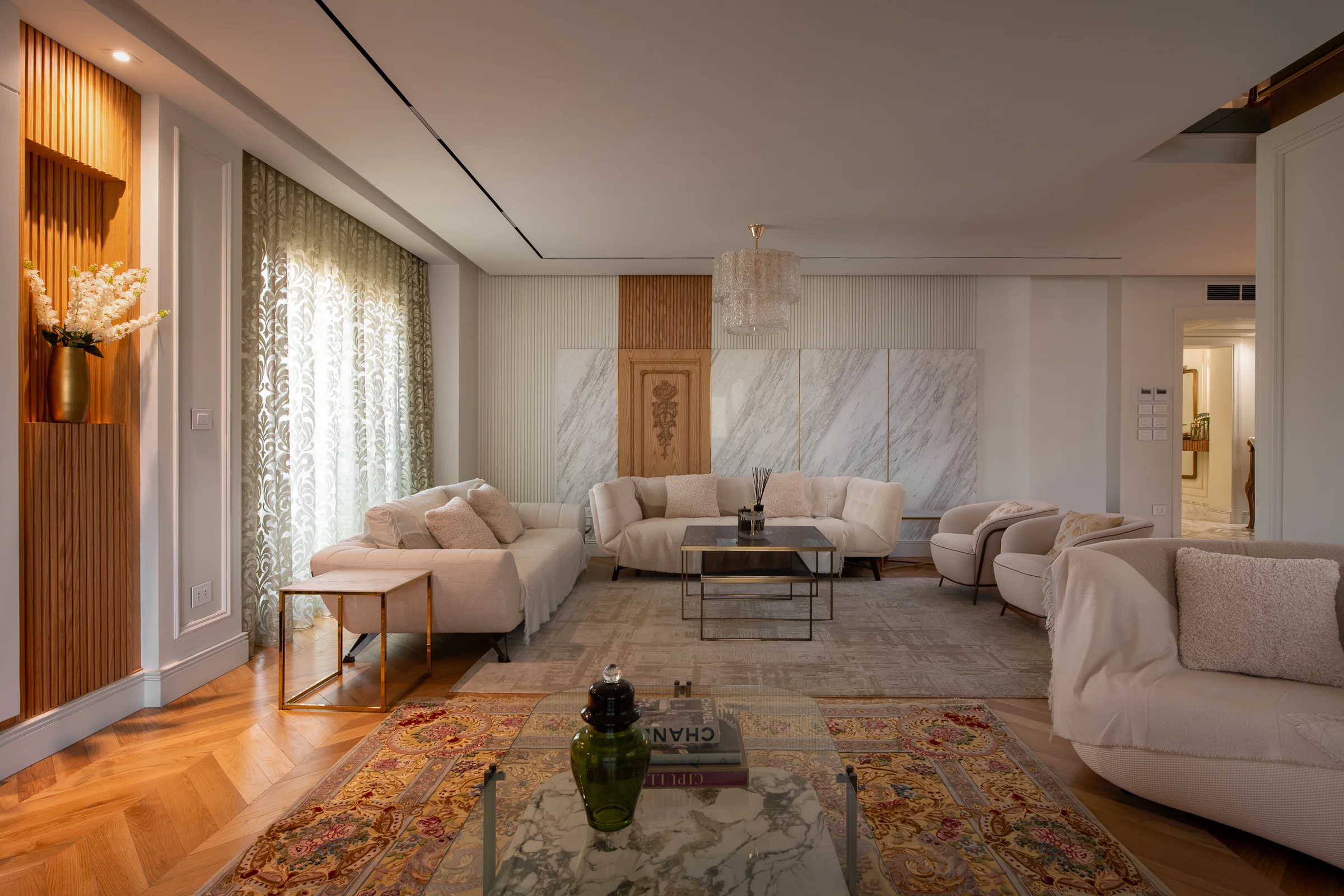 Reception wide: tufted seating, Persian rug, marble wall.