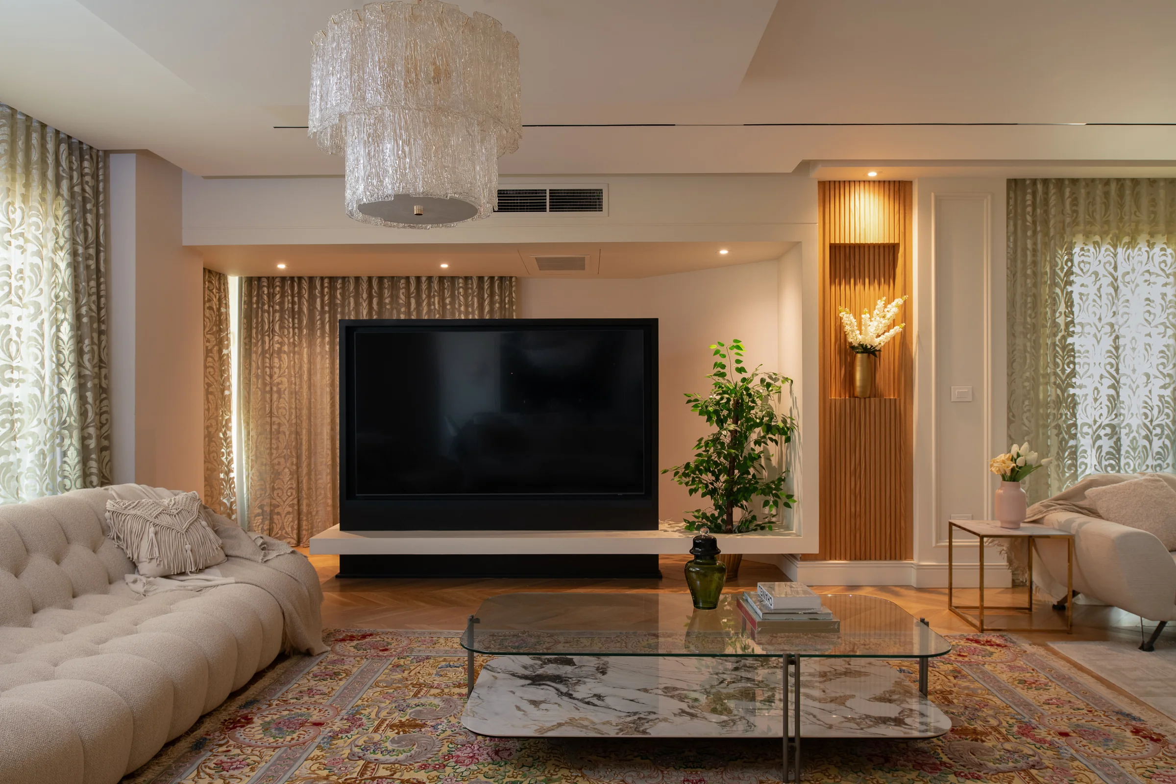 Tufted sofa and glass table under a crystal chandelier.