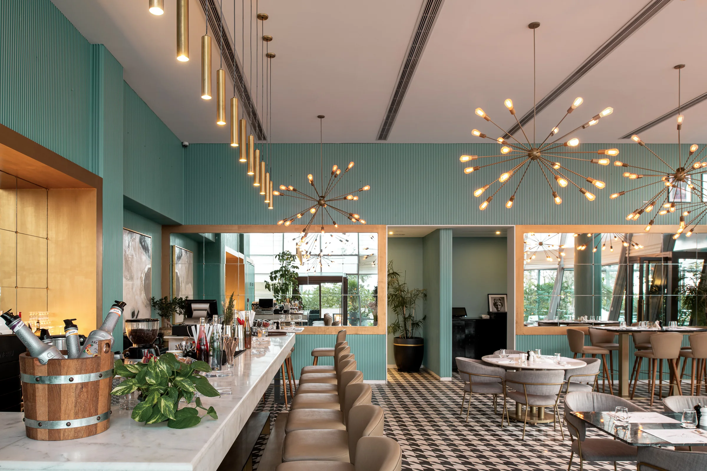 The dining room wide, brass chandeliers over teal panelling.