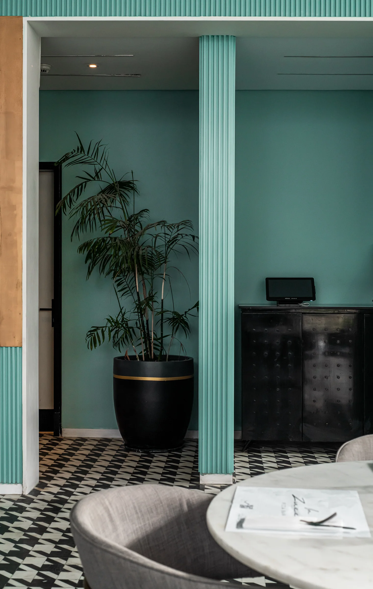 Banquette and ribbed teal wall, checkerboard underfoot.