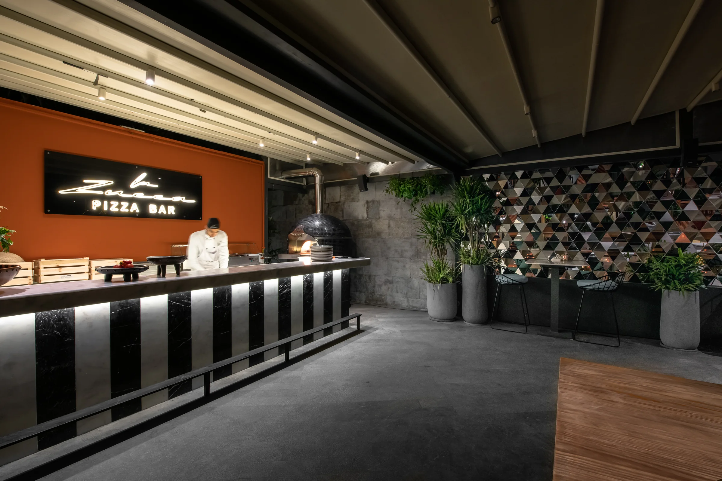A chef at the pizza counter, oven at the far end.