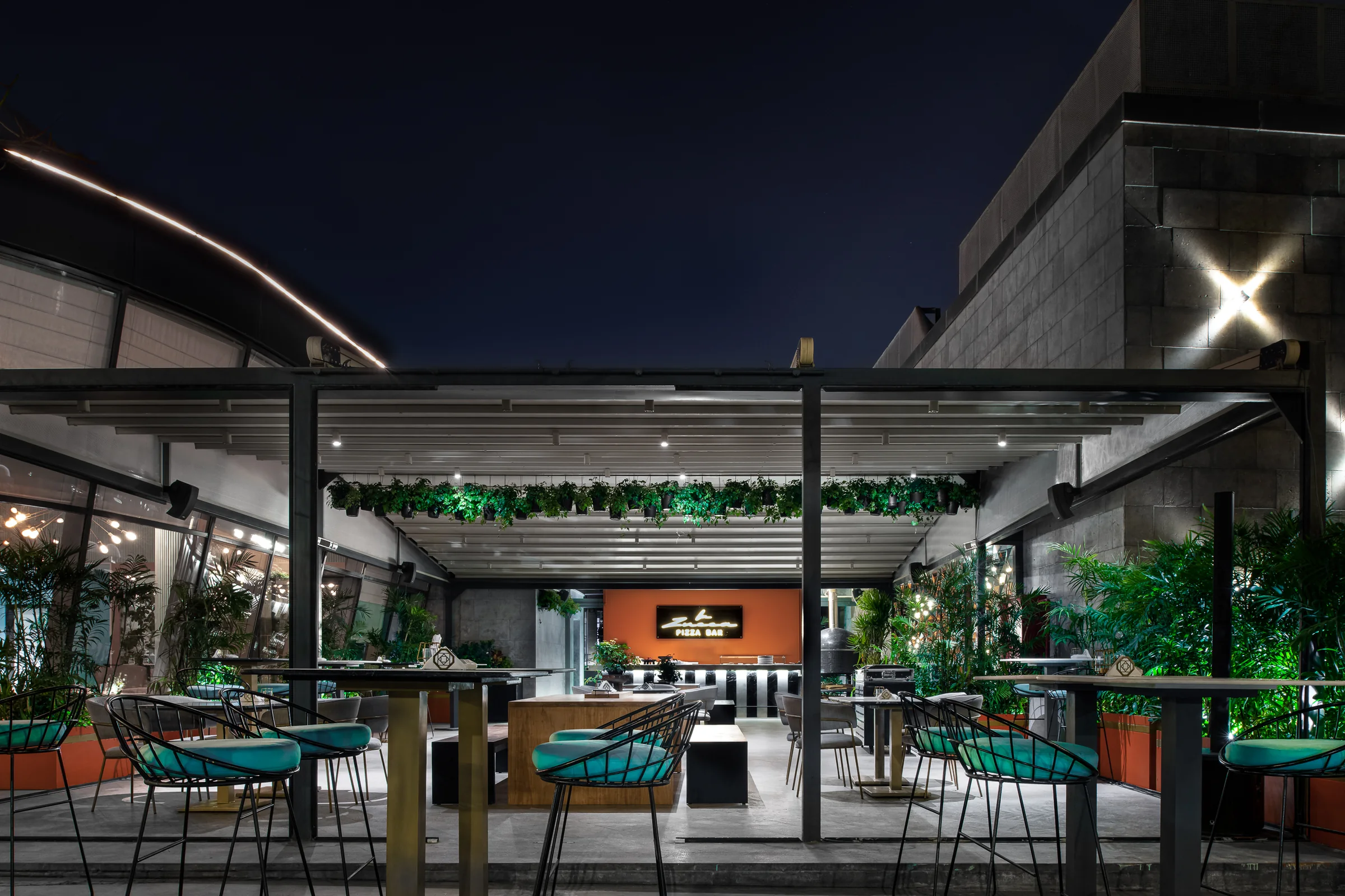 The terrace at night, string lights through the greenery.